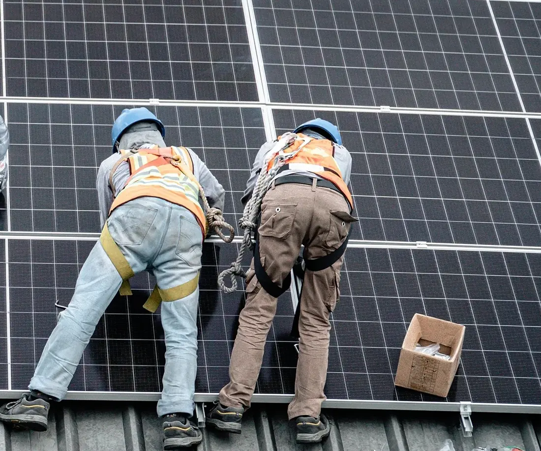 Two technicians laying solar panels onto the roof rails