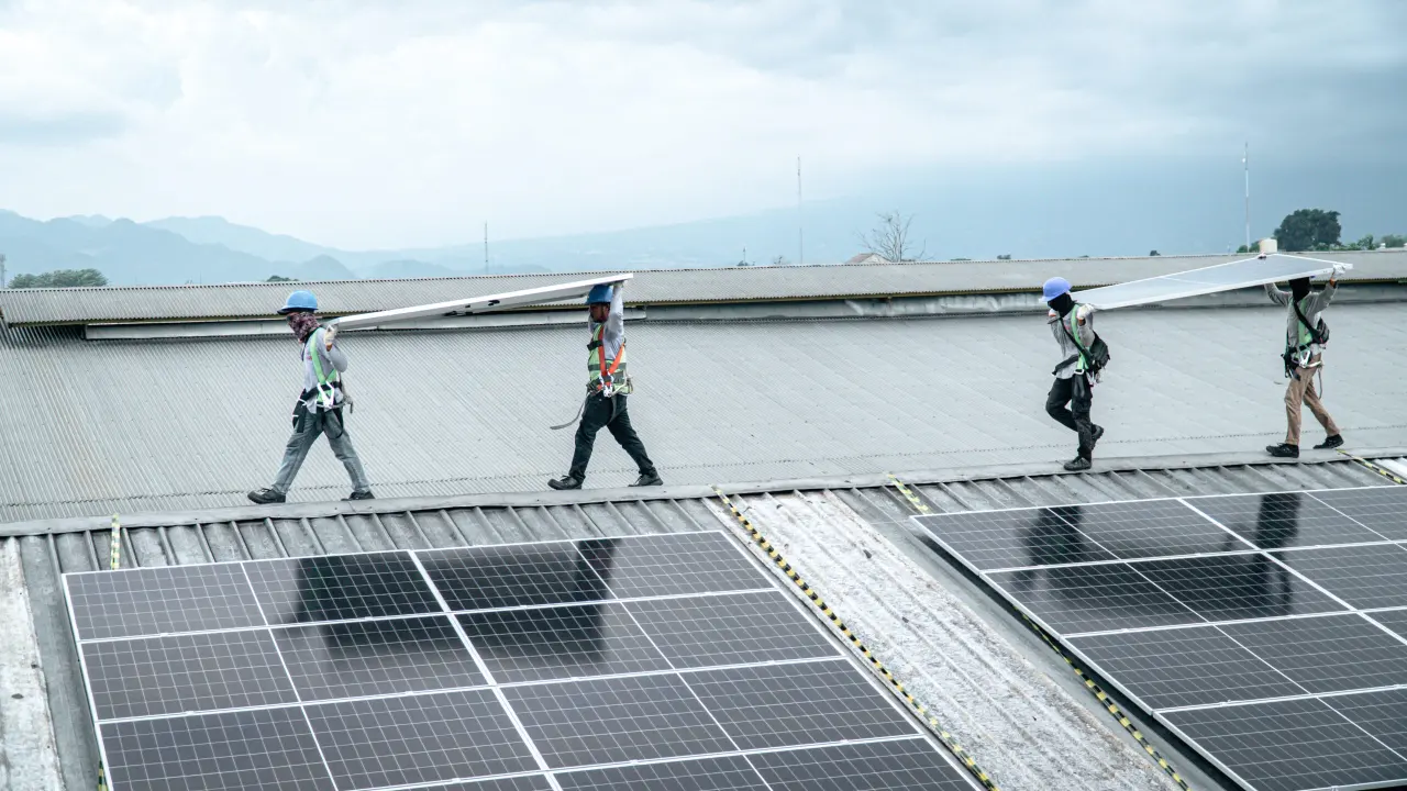 Team carrying solar panels across the factory roof